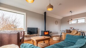 Ett mysigt vardagsrum med en soffa, ett soffbord, en tv, en öppen spis och en matplats med stolar och ett bord.