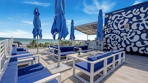 Terraza con asientos acolchados azules y sombrillas, con vista al océano.
