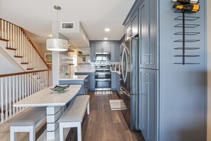 Una cocina moderna con gabinetes grises, electrodomésticos de acero inoxidable y una escalera de madera.