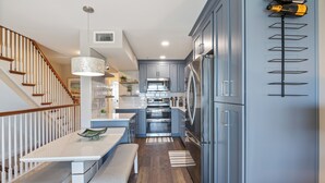 Une cuisine moderne avec des meubles gris, des appareils en acier inoxydable et un escalier en bois.