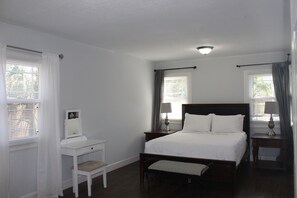 A bedroom with a bed, bedside tables, a chair, and a window with curtains. - The Oasis in Murray Hill - Centrally Located- sleeps 8-  WiFi-Cozy-Free Parking (Jacksonville)