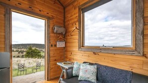Ein gemütliches Blockhaus-Interieur mit einer Couch, einem kleinen Tisch und einem Fenster mit Blick ins Freie.