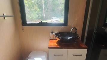 Ein kleines Badezimmer mit Toilette, Waschbecken und einem Fenster darüber.
