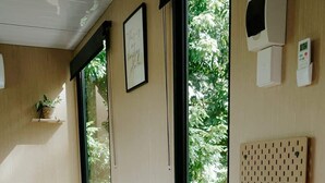 Un dormitorio moderno con cama, una mesita, un escritorio y vistas a zonas verdes.