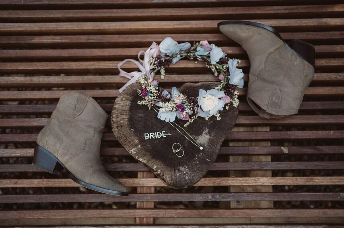 A wooden bench with a heart-shaped object on it, labeled 'BRIDE,' and a pair of boots.
