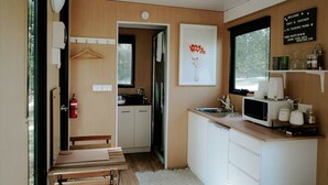 Una cocina compacta con microondas, pileta y una obra de arte enmarcada en la pared.