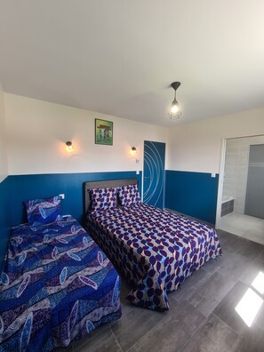 Una habitación con dos camas, una pared de acento azul, un cuadro enmarcado y una lámpara moderna.