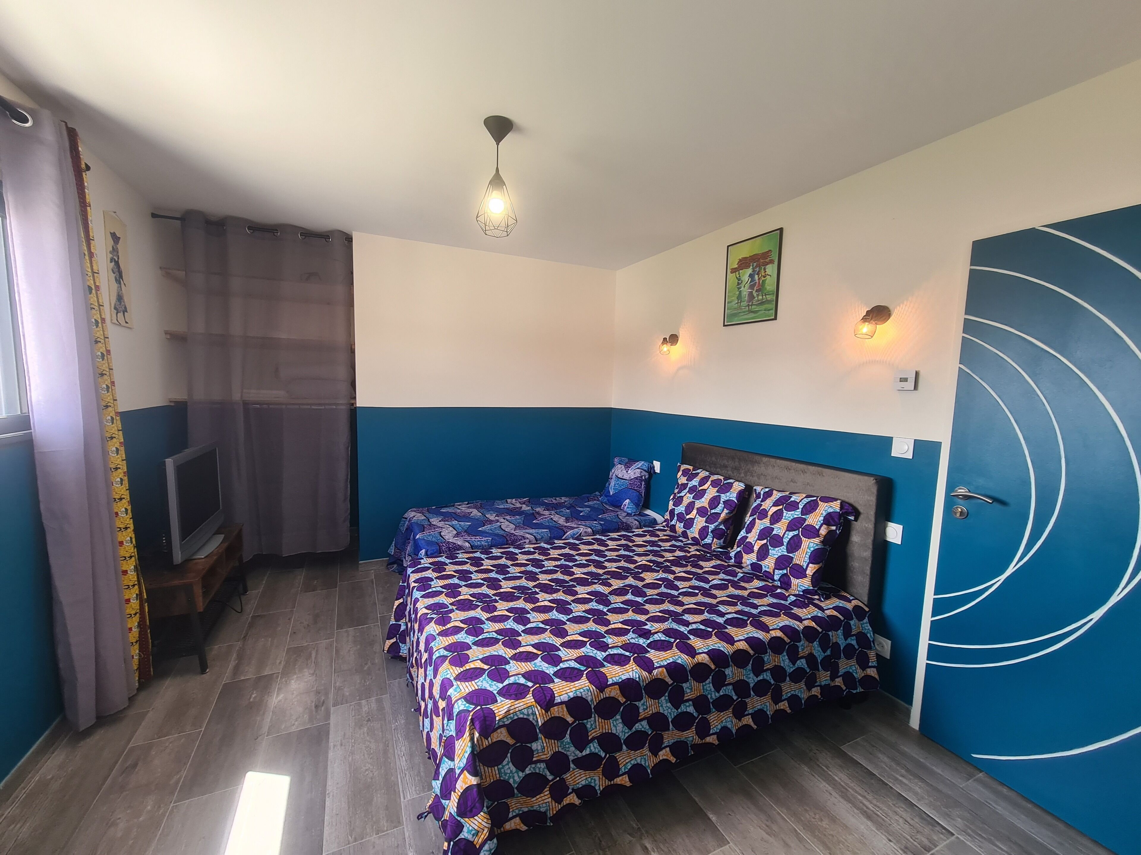 A bedroom with a bed, a TV, and a blue door.