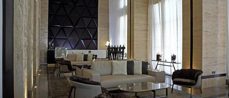 Un moderno vestíbulo de hotel con un conjunto de sofás, sillones y una mesa de centro.