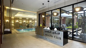 Un club de salud con piscina, equipamiento de ejercicio y una recepción.