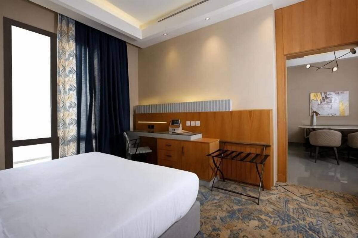 A hotel room with a bed, a desk, a chair, and a small table.