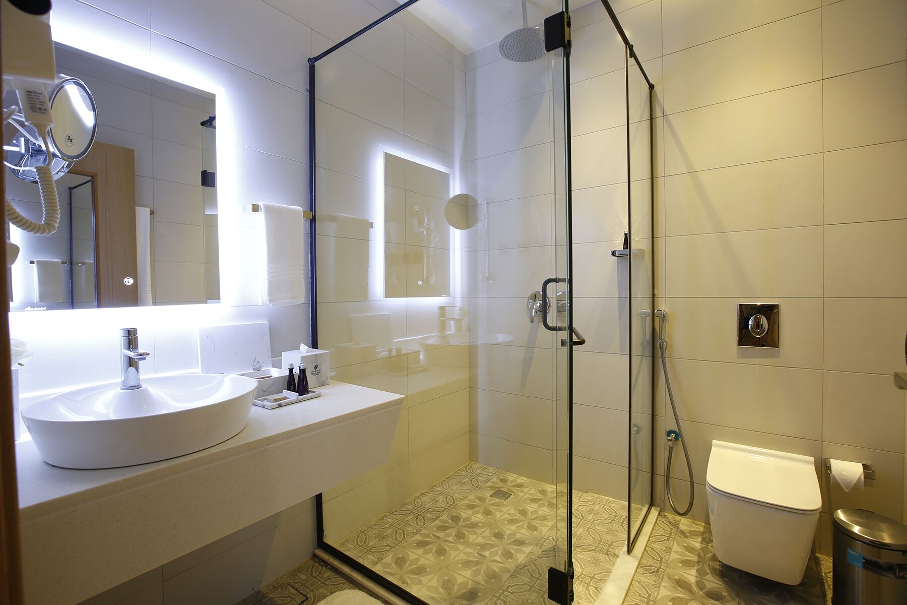 A modern bathroom with a glass-enclosed shower, a white sink, and a toilet.