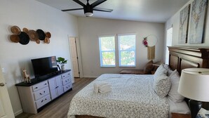 Une chambre à coucher comprenant un lit, une commode, un téléviseur et un ventilateur de plafond.