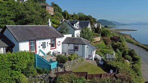 A coastal house with a staircase leading to a deck, surrounded by lush greenery and a view of the sea. - Arthur's Seat,  elevated cottage, sea views (Dunoon)