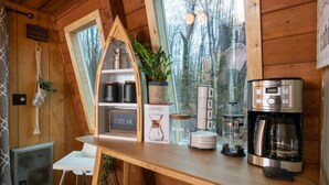 A wooden cabin interior with a kitchen area featuring a coffee maker, a Chemex coffee pot, and a glass carafe. - Lake Naomi A-Frame Cabin, Pet Friendly, (Pocono Pines)