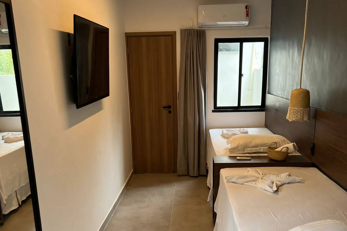 Een hotelkamer met een bed, een stoel, een televisie en een raam met gordijnen.