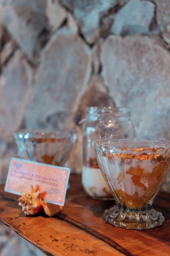A wooden table with three glass containers filled with granola and a small sign. - Maly Boutique Hotel (Fortaleza)
