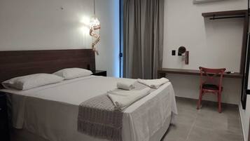 Una habitación de hotel con una cama grande, un escritorio, una silla y un equipo de aire acondicionado.