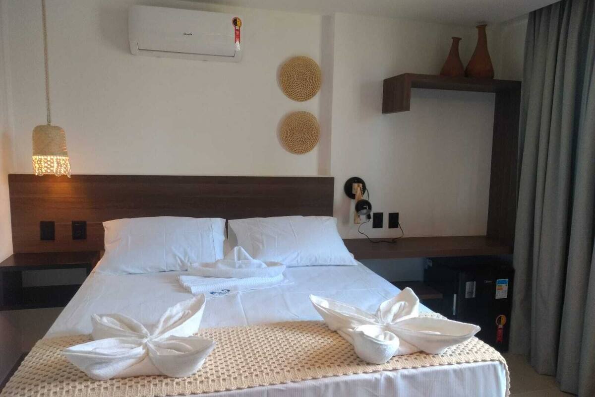 Een hotelkamer met een net opgemaakt bed, een wandairconditioner en decoratieve wandtapijten.