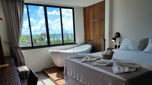Un dormitorio moderno con una cama grande, una bañera y vista al océano.
