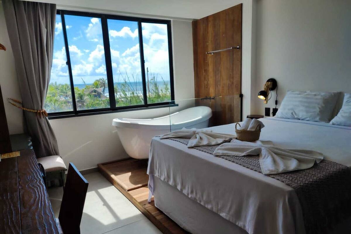 Een moderne slaapkamer met een groot bed, een badkuip en uitzicht op de oceaan.