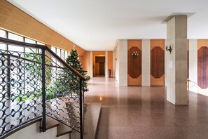 A modern hotel corridor with a staircase, a Christmas tree, and wooden doors. - Your prestigious stay in Milan - Navigli/Tortona District (Milano)