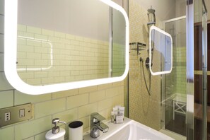 Ein Badezimmer mit einem großen Spiegel, einer Dusche und einem Waschbecken.