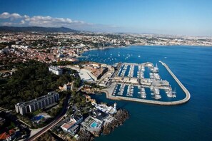 Vista aérea de una ciudad costera con un puerto deportivo, zonas residenciales y un gran complejo hotelero.