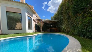 A swimming pool with a curved edge, surrounded by a well-maintained lawn and a hedge. - Design Guincho Villa (Cascais)