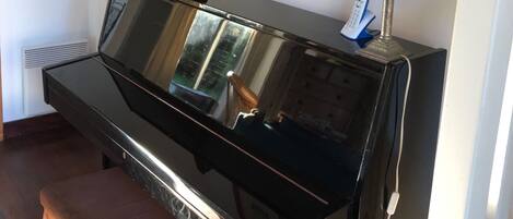 A piano with a bench, a lamp, and a framed picture on the wall.