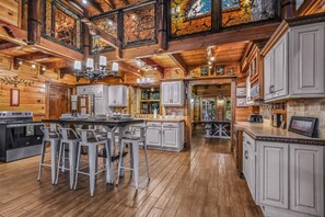 A spacious kitchen with a central island, bar stools, and a large dining table.