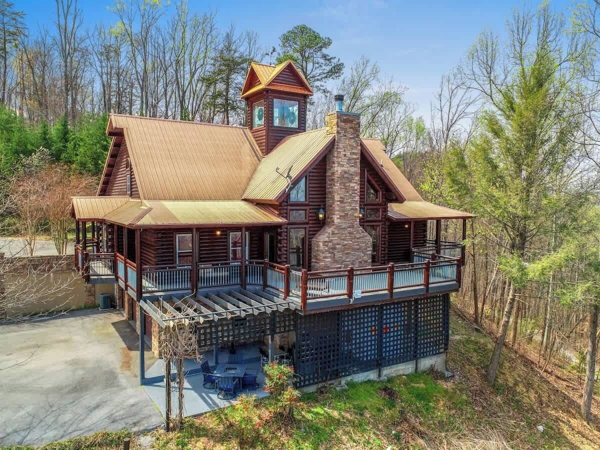 A large, multi-level cabin with a prominent chimney, a balcony, and a small tower-like structure.