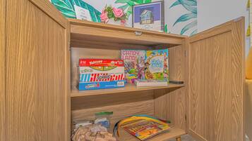 Un mueble de madera con juegos de mesa y juguetes para niños.