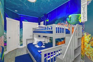 A room with bunk beds, an aquarium, and a mural of an underwater scene.