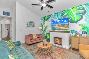 A living room with a sofa, a coffee table, a fireplace, and a large wall mural.