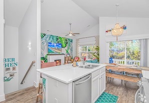 A modern kitchen with a central island, a dining area with a bench, and a view of the outdoors.