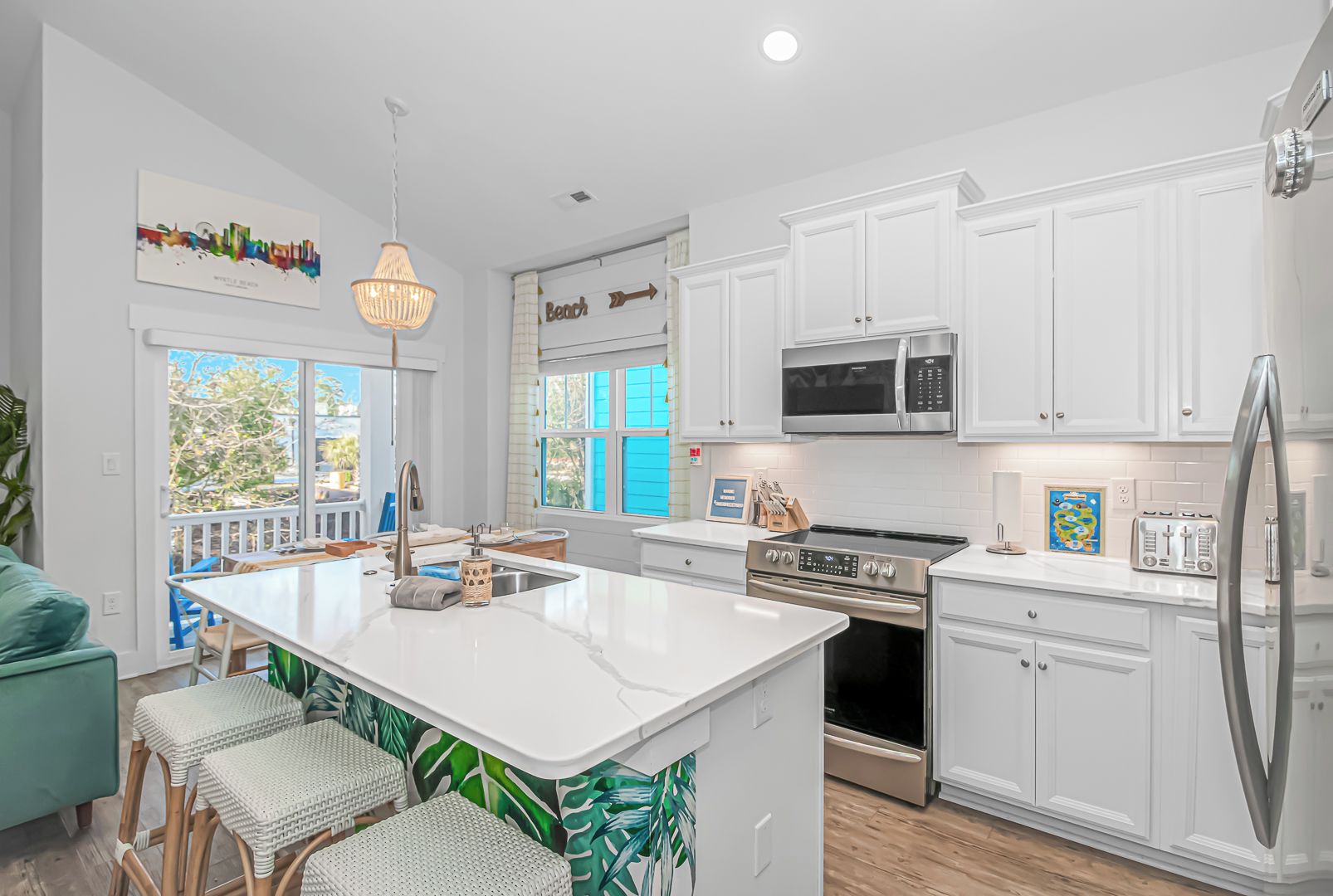 A modern kitchen with white cabinetry, stainless steel appliances, and a central island with seating.
