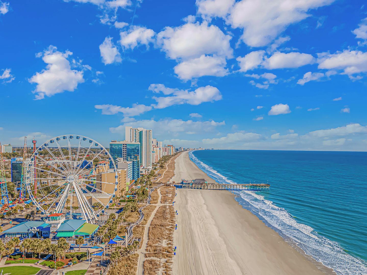 A coastal cityscape with a beach, a Ferris wheel, and modern buildings.