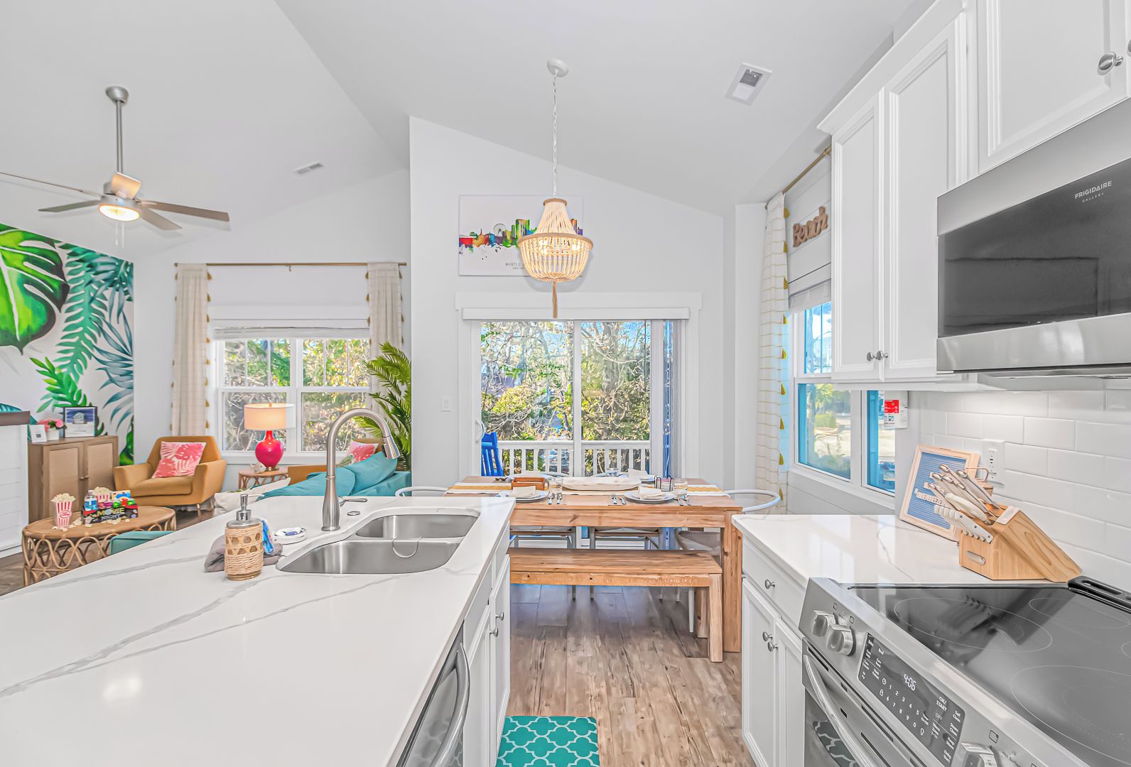 A modern kitchen with white cabinetry, a large island with a sink, and a dining area with a wooden table.