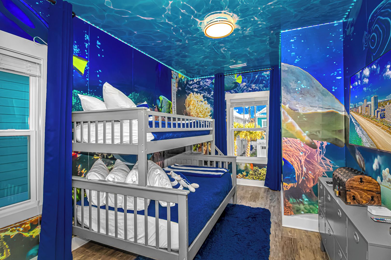 Una habitación con literas, una ventana y un mural de escenas submarinas.