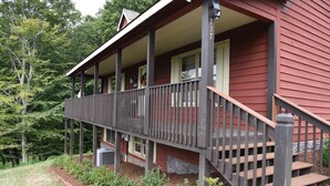 A wooden house with a porch, a staircase, and a small garden area. - Amazing Views!! Creekside Cabin, Wrap Around Porch, Close to Town! Dogs Welcome! (Hiawassee)