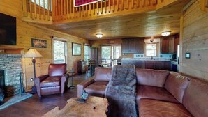 A rustic cabin interior with a stone fireplace, leather furniture, and a wooden ceiling. - Amazing Views!! Creekside Cabin, Wrap Around Porch, Close to Town! Dogs Welcome! (Hiawassee)
