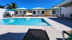 A pool area with lounge chairs and a covered seating area. - Tropical 1 Bedroom Cabana on Private Oasis (Maya Beach)