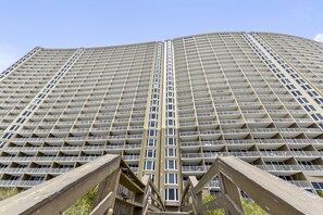 Um edifício alto com fachada em grade, várias varandas e um elemento vertical central.