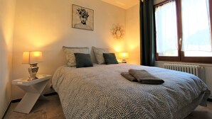 Una camera da letto con un letto grande, due comodini con lampade, un'opera d'arte appesa al muro e una finestra con tende.