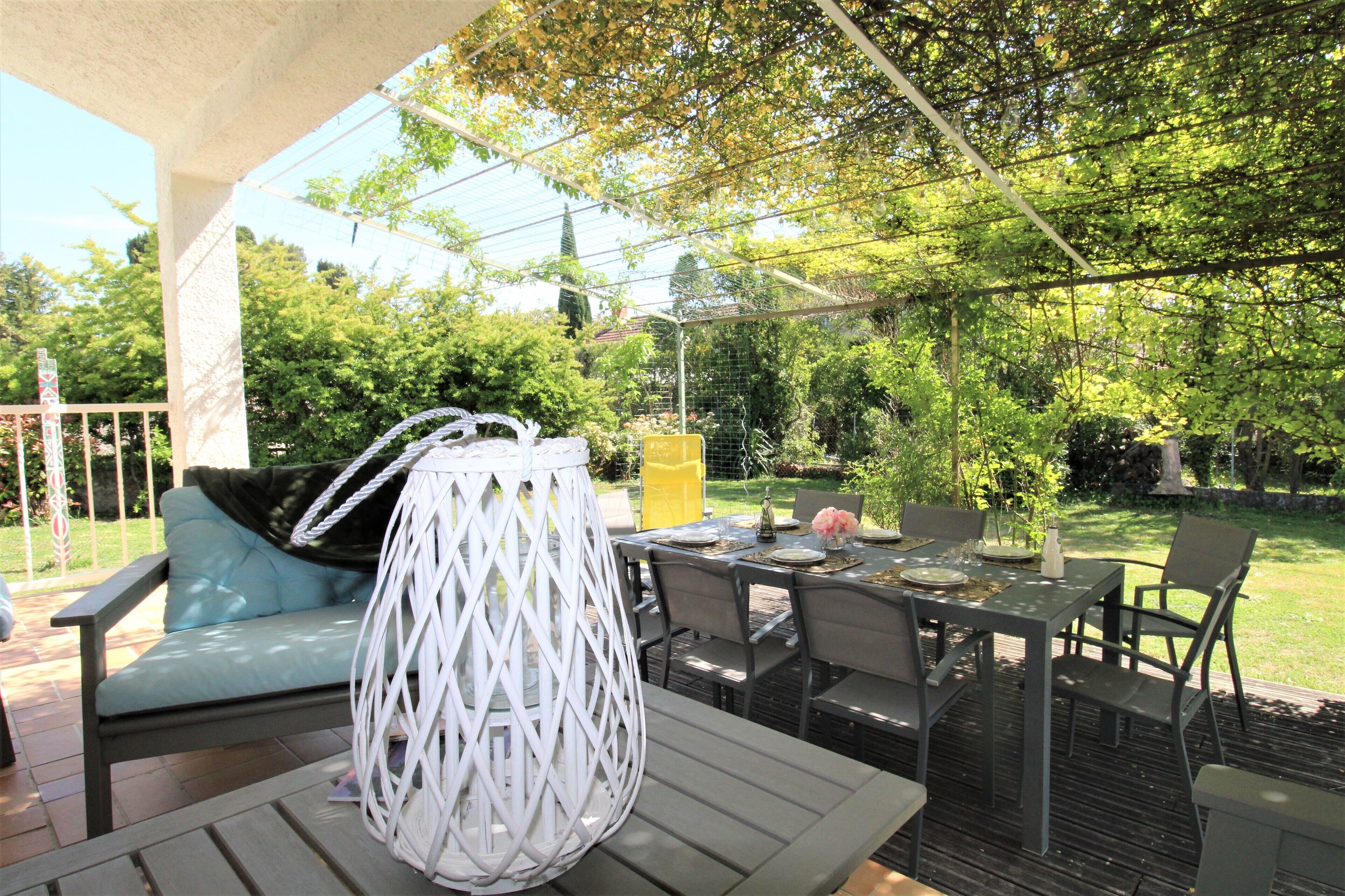 An outdoor patio with a dining table, chairs, and a cushioned seating area.