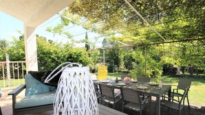 Un patio esterno con tavolo, sedie e un'area salotto con cuscini.