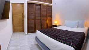 Una camera da letto con un letto, due lampade ai comodini, un armadio in legno e un televisore montato a parete.