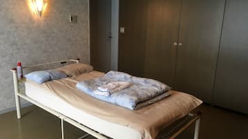 A single bed with a headboard, a wall-mounted light fixture, and a wardrobe.