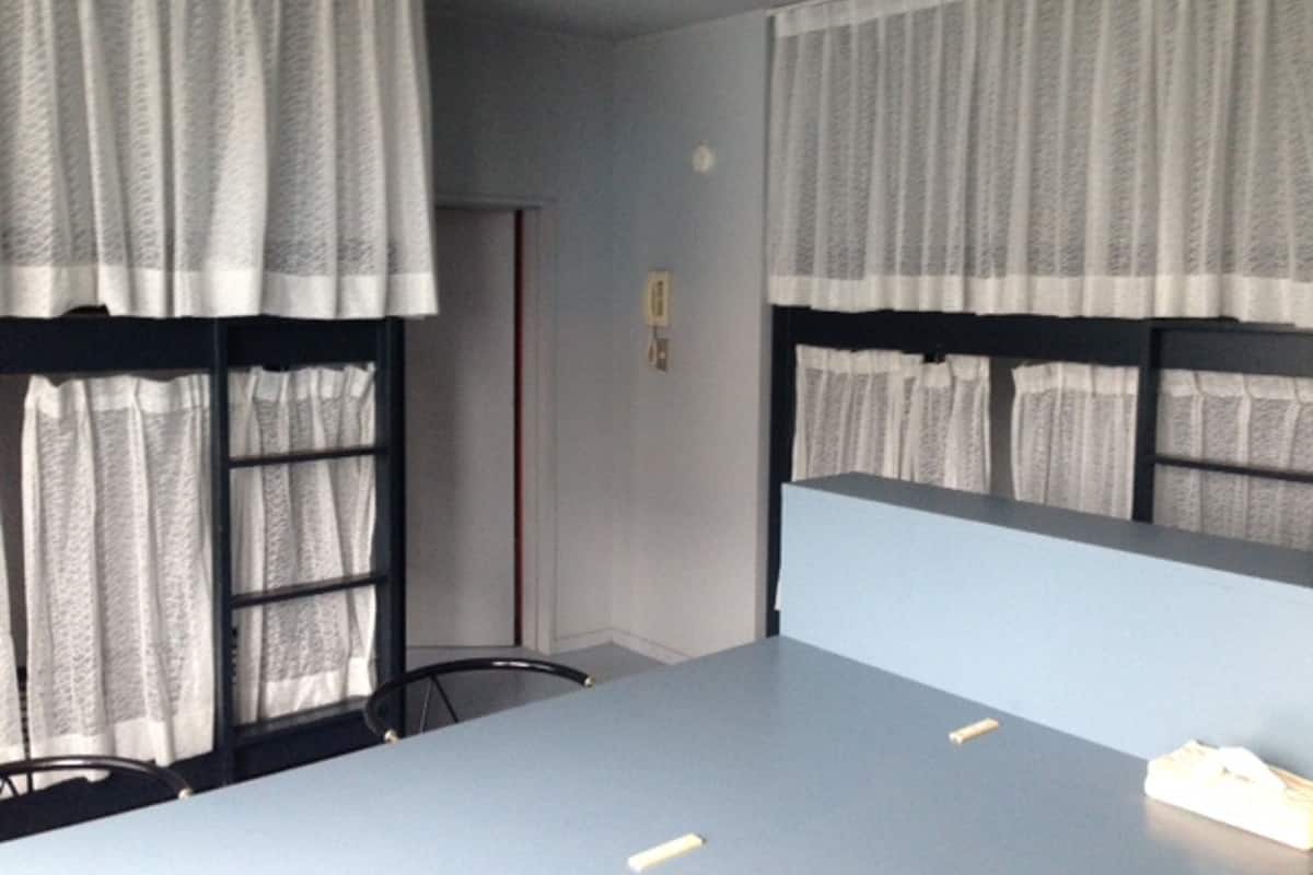 Een kamer met stapelbedden, een bureau en een stoel.